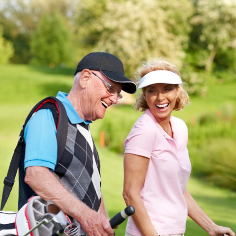 Older couple smiling on golf course