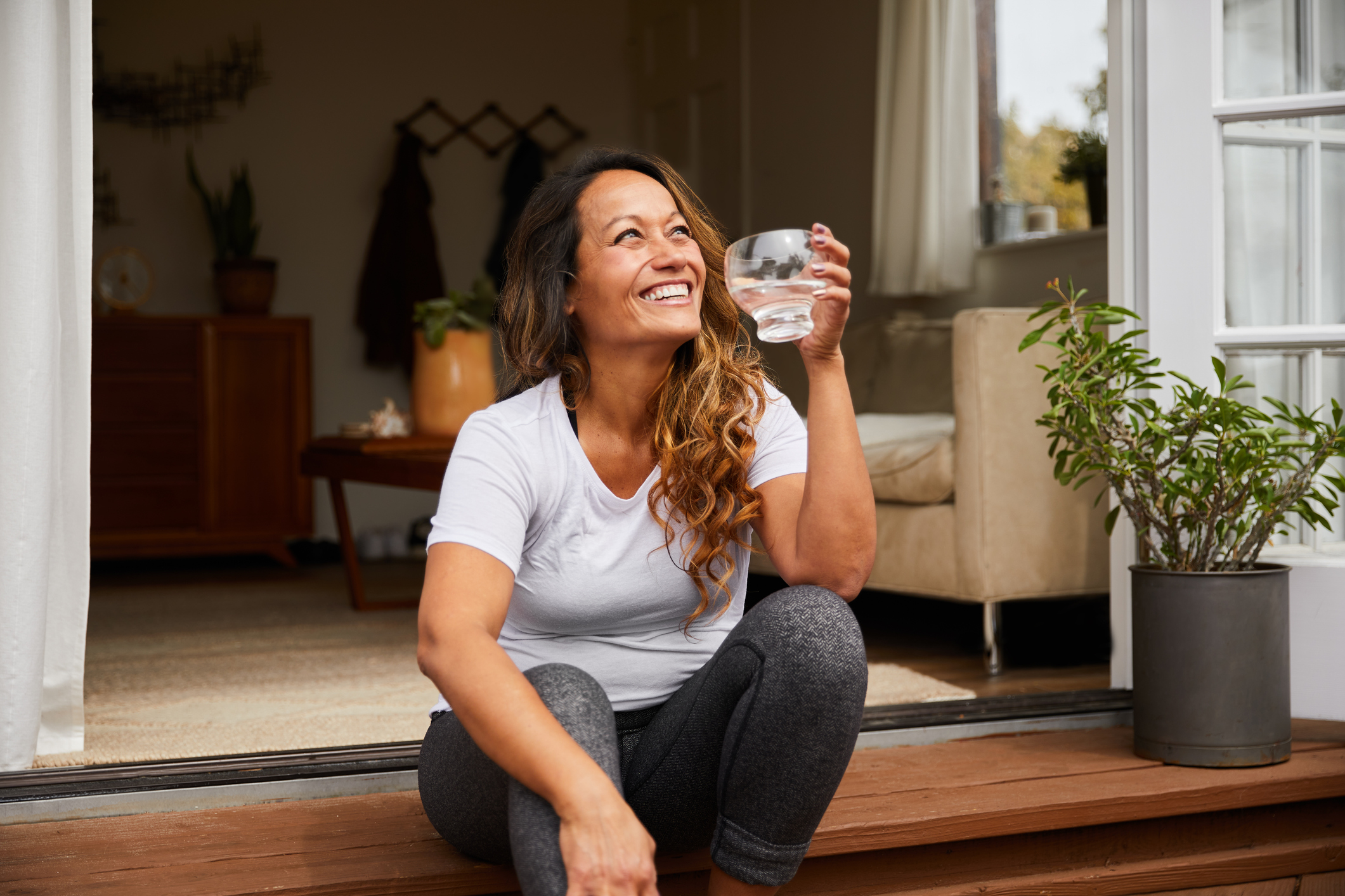 Smiling mature woman sitting on her patio drinking water Navigating the Stages from Perimenopause to Menopause