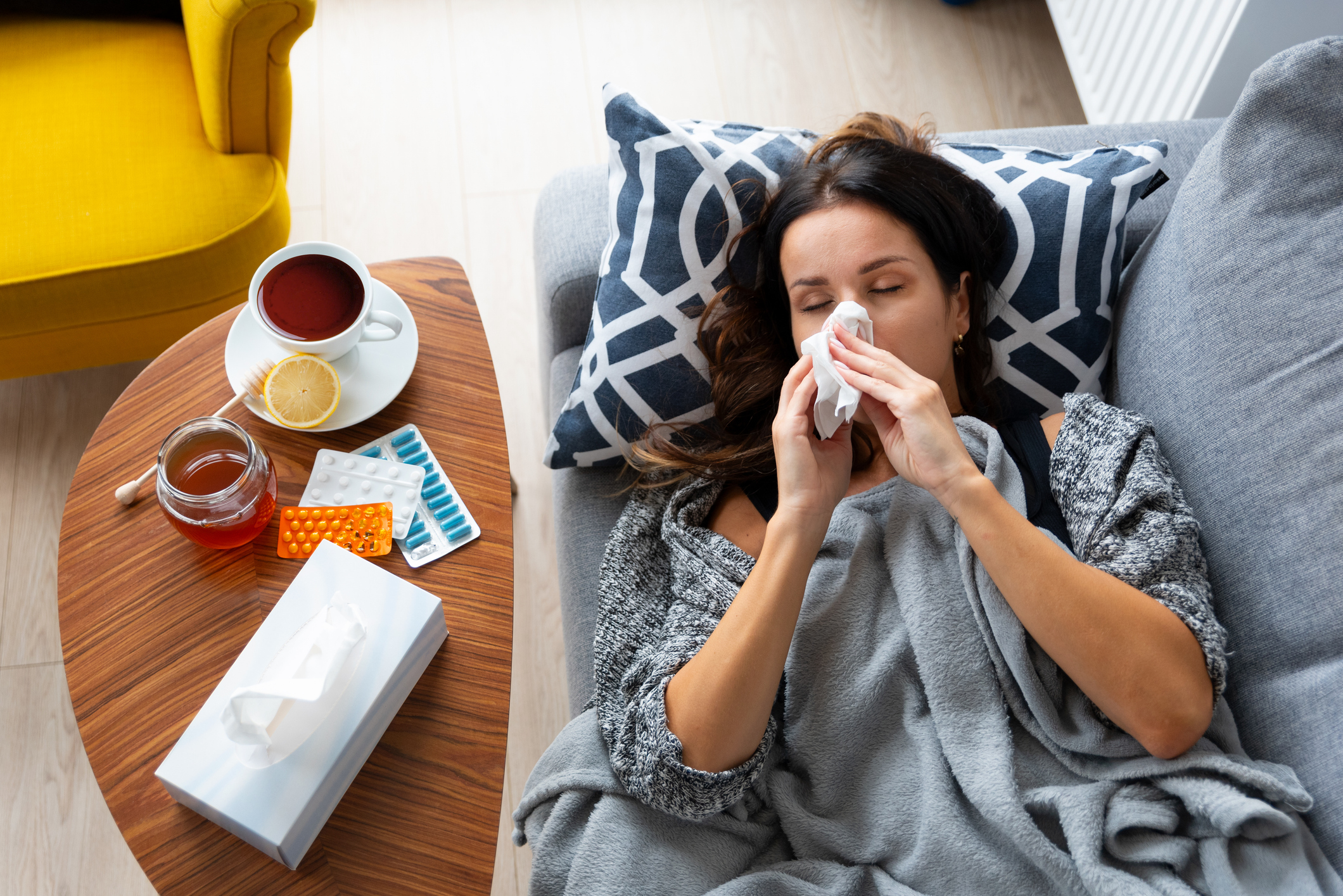 Woman is laying on a couch with a tissue Navigating the Stages from Perimenopause to Menopause